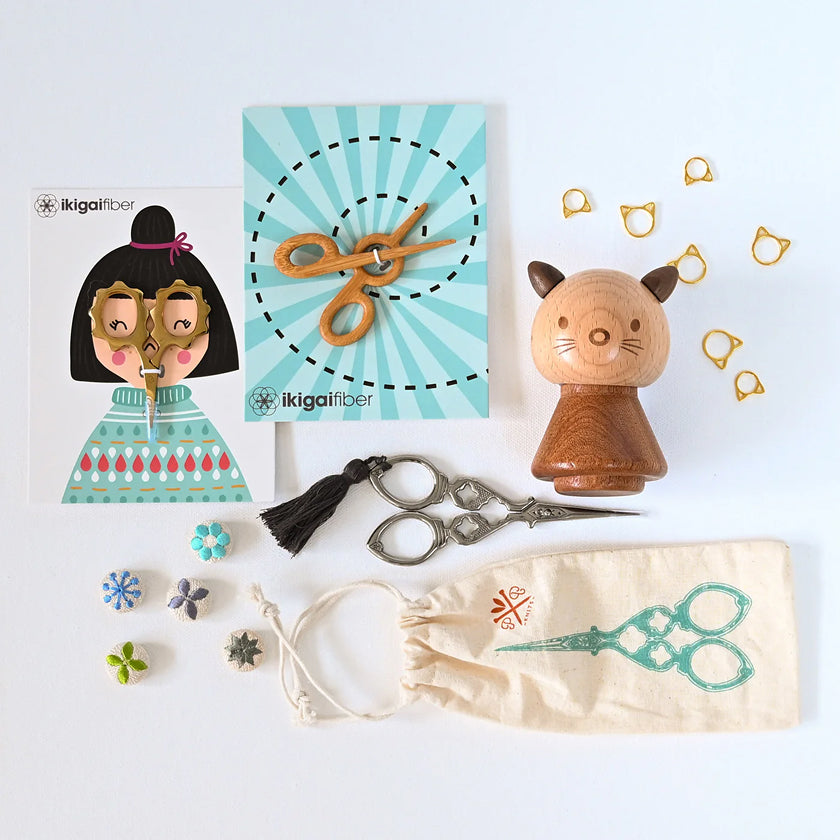 Collection of decorative items including a wooden cat figure, scissors, and a small bag on a light blue background.